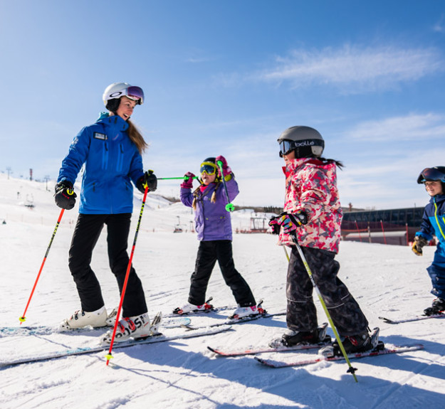 WinSport Instructor with a group of children learning how to ski on snow